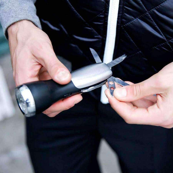 10 Function Flashlight Survival Tool Distinctive Mad Man flash light with several hidden tools in the handle. Great for the man on the go. Includes, scissors, saw blade, knife. Tools include , scissors, saw blade, knife. Stainless steel with matte black contrast There ideal men's accessory for home and car Material: Stainless Steel | Plastic Dimensions: 6" x 2.5"